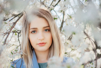 Outdoors photo of beautiful young lady in the garden of cherry blossoms