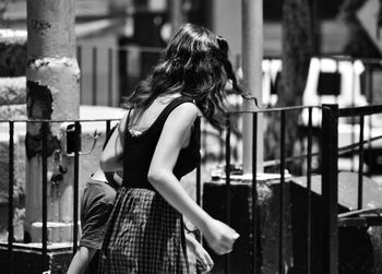 Rear view of woman standing against railing