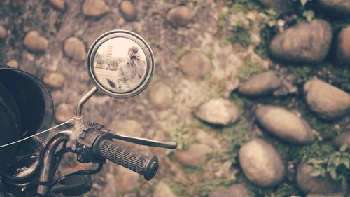 Reflection of man photographing on motorcycle mirror