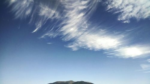 Low angle view of sun shining through clouds