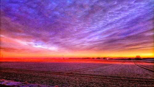 Scenic view of field against dramatic sky during sunset