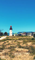 Lighthouse on field against clear blue sky