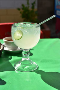 Large glass of lemonade with lime slice in glass and plastic straw, served in mexican restaurant 