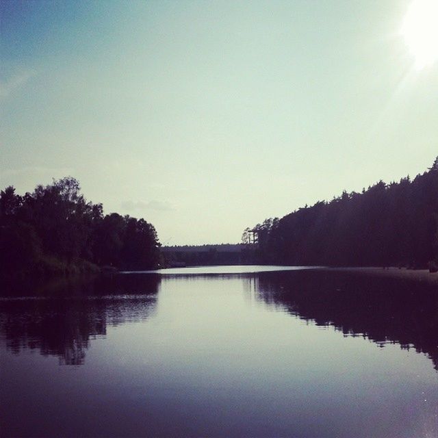 reflection, water, tranquil scene, tranquility, lake, tree, scenics, beauty in nature, waterfront, sun, nature, sunlight, clear sky, sky, idyllic, silhouette, calm, river, copy space, outdoors