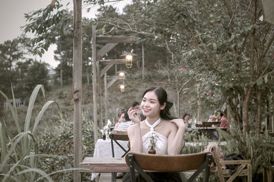 Portrait of young woman sitting on chair at park