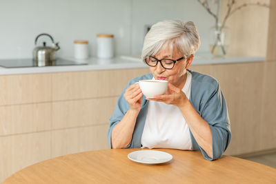 Portrait of young woman drinking coffee at home