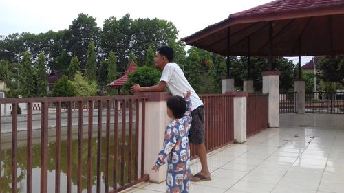 Side view of woman standing by railing against trees