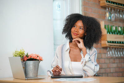 Portrait of young woman using laptop at table