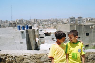 Rear view of boys and cityscape against clear sky