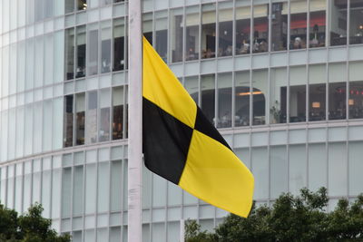 Yellow flag against sky in city