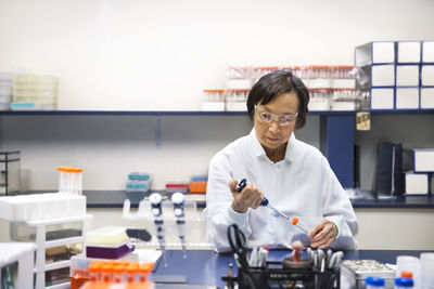 Senior female scientist using pipette in laboratory