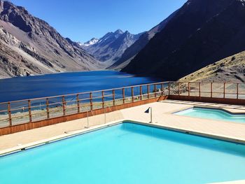 Swimming pool by mountains against blue sky