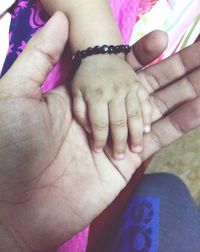 Close-up of father holding baby hand