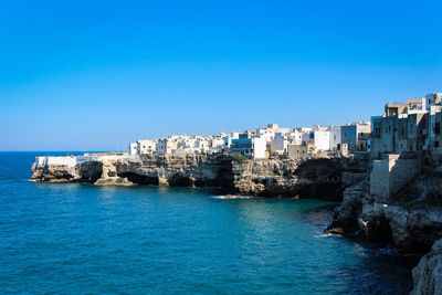 Sea by buildings against clear blue sky