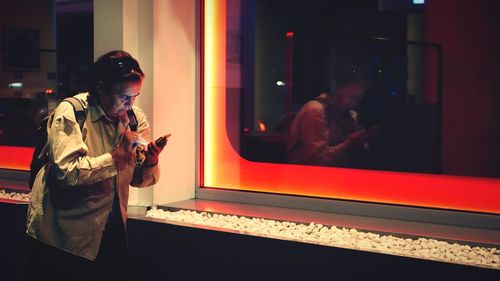 Man photographing through window at night