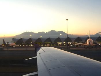 Airplane on runway against sky during sunset