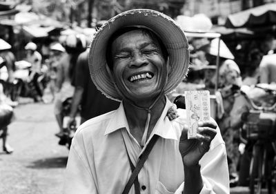 Cheerful mature woman with eyes closed standing on street