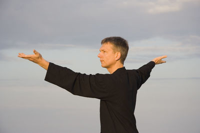 Man practicing tai chi against sky