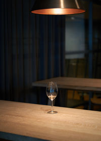 Illuminated lamp with wine glass on table in restaurant