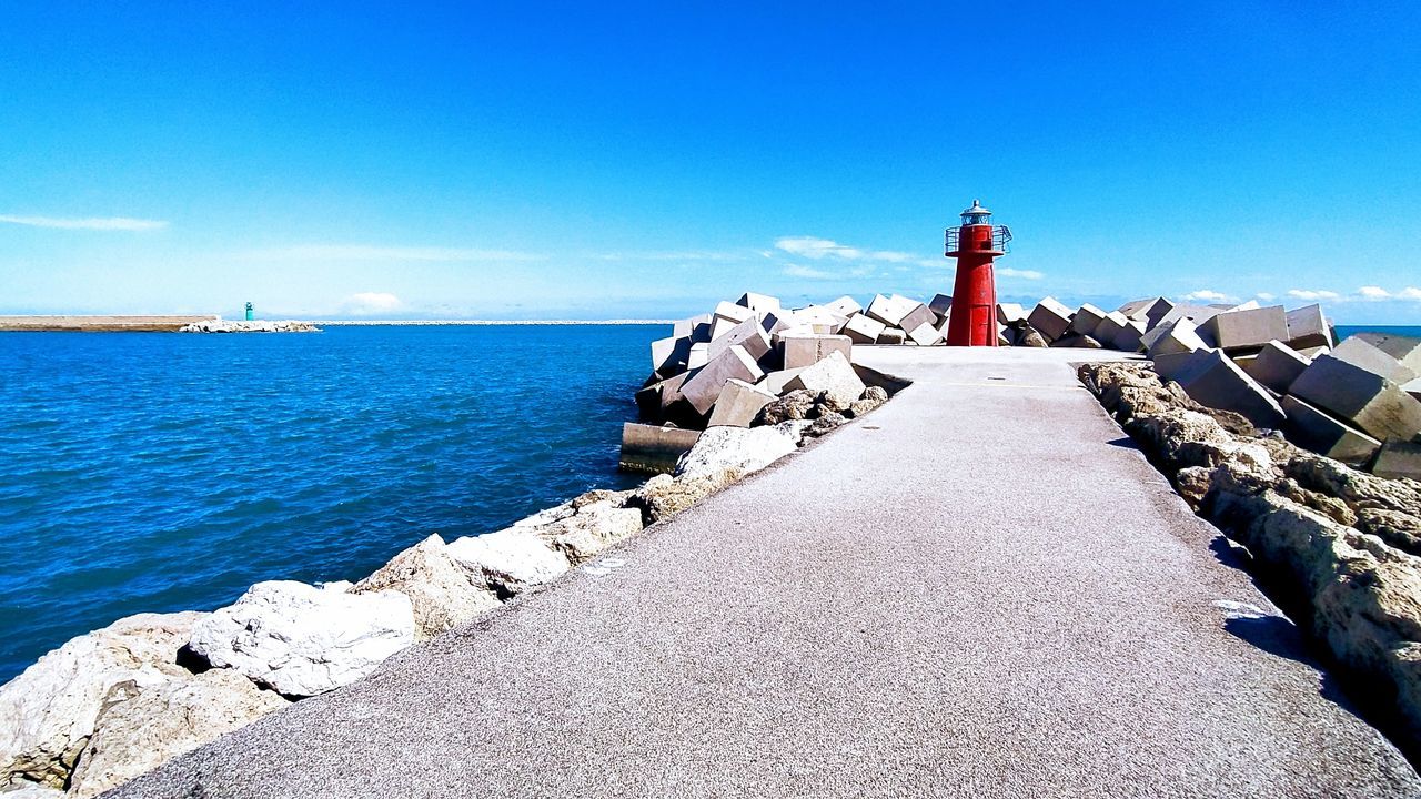 water, sea, sky, direction, security, built structure, lighthouse, protection, guidance, safety, architecture, blue, building exterior, tower, nature, day, building, rock, the way forward, no people, horizon over water, outdoors, groyne