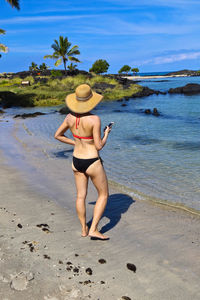 Rear view full length of sensuous woman standing in bikini at beach