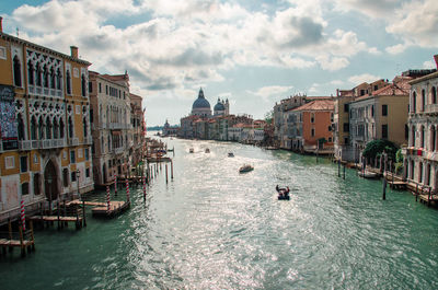 Boats in canal amidst buildings in city