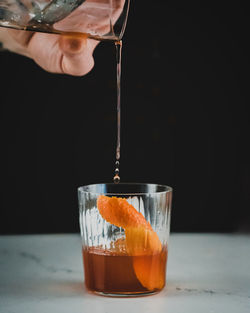 Close-up of hand pouring drink in glass