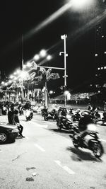 People on road against illuminated city at night