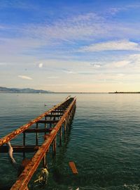 Pier on sea against cloudy sky