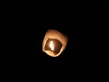 Low angle view of illuminated lamp against black background