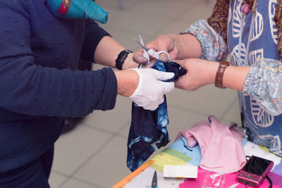 Midsection of people cutting clothes