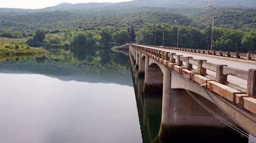 Bridge over river by mountains against clear sky