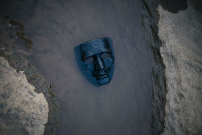 Selective focus the black plastic mask is placed in the rocky river water. and evil mask 