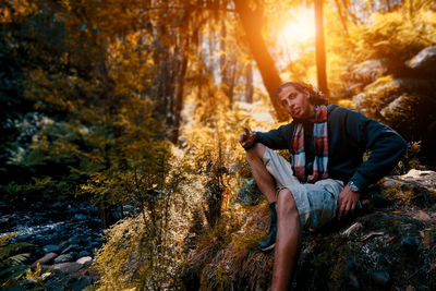 Young man sitting on rock in forest