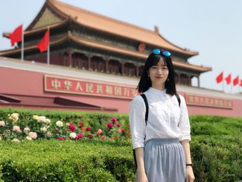 Portrait of smiling young woman standing against building