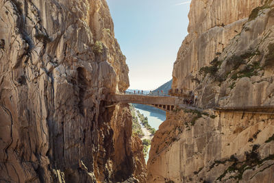 Bridge over river amidst rock formation against sky