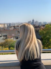 Rear view of woman against sky in city