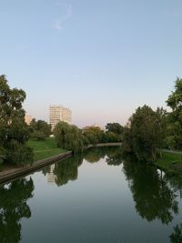 Reflection of trees and buildings in lake against sky