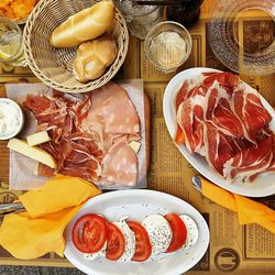 Directly above shot of meat with salad and breads on table