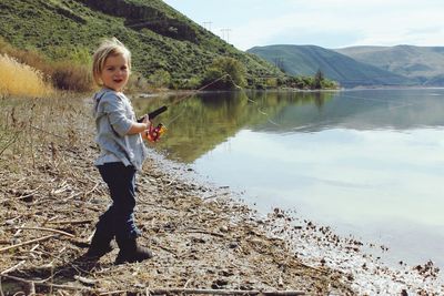 Portrait of girl standing by lake against mountains