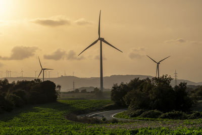 Road in agricultural fields with wind turbines generating clean electricity in catalonia spain