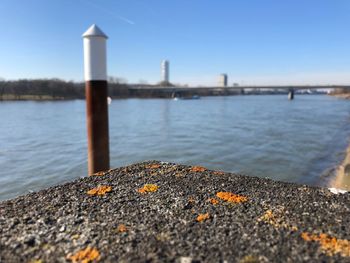 Close-up of wooden post by river against clear sky