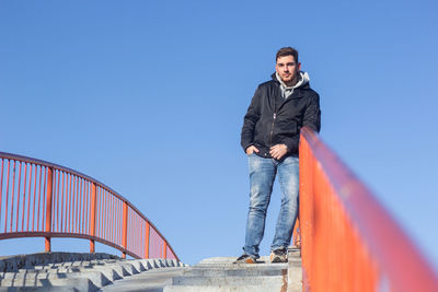 Low angle view of man standing against clear blue sky