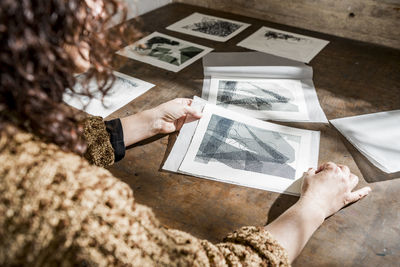 Female artist inspecting some pieces of hand made printings.