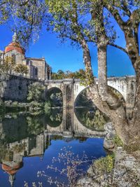 Arch bridge over river against sky