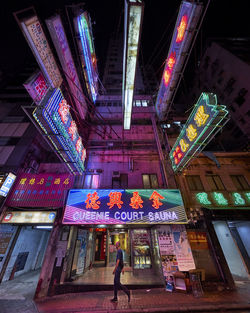 Low angle view of woman standing on illuminated building at night