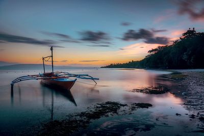 Sailboats in sea against sky during sunset