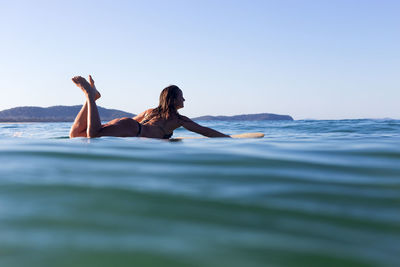 Woman relaxing on beach against sky