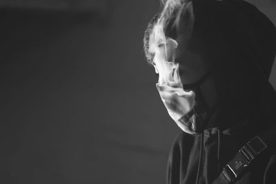 Close-up of man wearing mask while smoking against wall