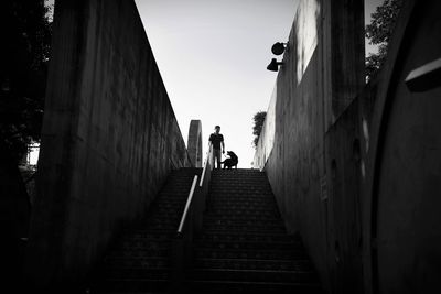 Low angle view of man with dog on steps against sky